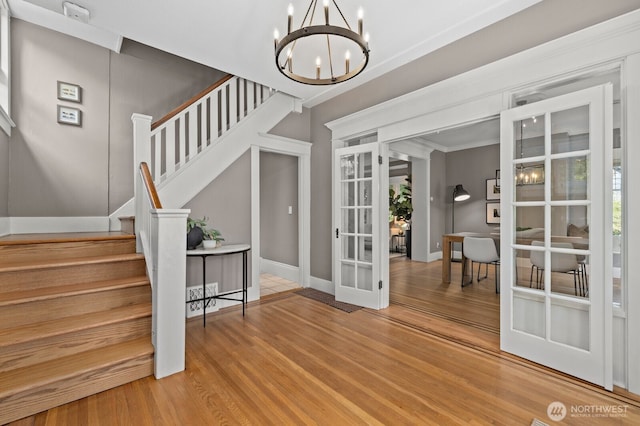 2159 10th Ave W, Seattle, WA 98119 - entrance foyer featuring french doors, a chandelier, stairs, wood finished floors, and ornamental molding