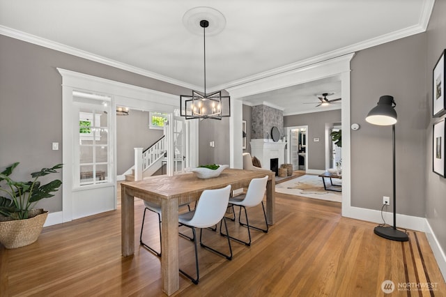 2159 10th Ave W, Seattle, WA 98119 - dining room with stairs, wood finished floors, ceiling fan, a large fireplace, and crown molding
