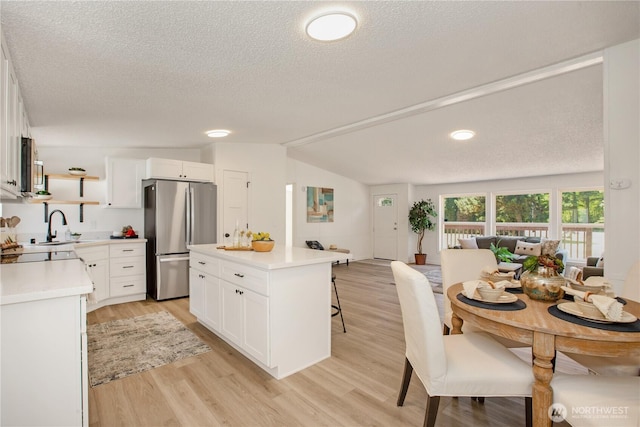 36715 Allen Rd S, Roy, WA 98580 - kitchen with freestanding refrigerator, a kitchen bar, light countertops, a textured ceiling, and open floor plan