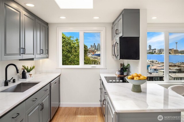 2301 Fairview Ave E Unit 404, Seattle, WA 98102 - kitchen featuring gray cabinetry, stainless steel appliances, light wood-style flooring, recessed lighting, and light stone countertops