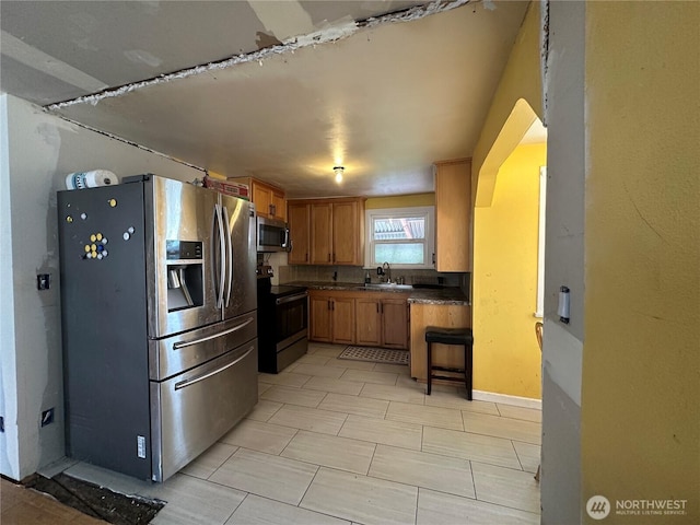 10204 19th Ave SW, Seattle, WA 98146 - kitchen featuring stainless steel appliances, dark countertops, brown cabinetry, and arched walkways
