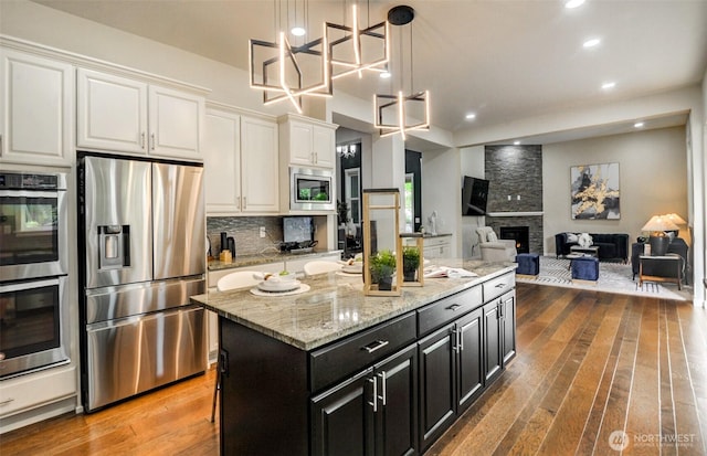 5708 197th Pl SE, Bothell, WA 98012 - kitchen featuring appliances with stainless steel finishes, hardwood / wood-style flooring, white cabinetry, dark cabinetry, and a kitchen island
