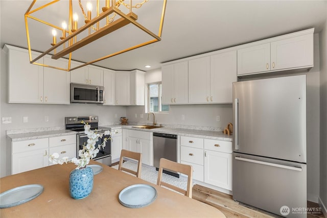 1604 W Market St, Aberdeen, WA 98520 - kitchen featuring appliances with stainless steel finishes, white cabinets, light countertops, hanging light fixtures, and light wood-style floors