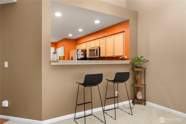 6547 Lindsay Ave SE Unit 18C, Auburn, WA 98092 - kitchen featuring stainless steel microwave, freestanding refrigerator, a breakfast bar, light colored carpet, and recessed lighting