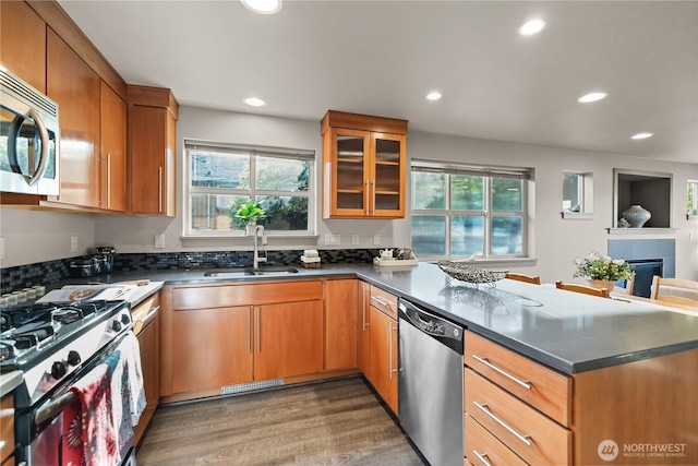 923 N 85th St Unit A, Seattle, WA 98103 - kitchen featuring stainless steel appliances, a peninsula, glass insert cabinets, recessed lighting, and wood finished floors
