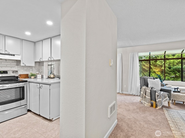 4920 200th St SW Unit A201, Lynnwood, WA 98036 - kitchen with stainless steel range with electric stovetop, white cabinetry, light countertops, decorative backsplash, and under cabinet range hood