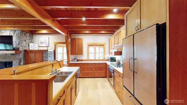156 Poechmann Rd, Okanogan, WA 98840 - kitchen with appliances with stainless steel finishes, under cabinet range hood, light wood-style flooring, a stone fireplace, and light countertops