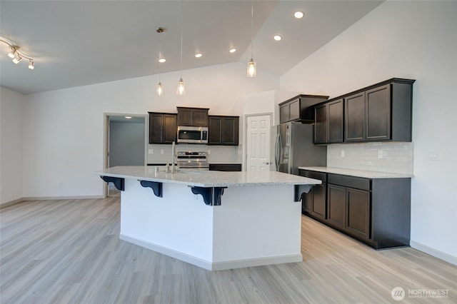 232 Jett Ct, Montesano, WA 98563 - kitchen with appliances with stainless steel finishes, light wood-style flooring, a kitchen breakfast bar, backsplash, and recessed lighting