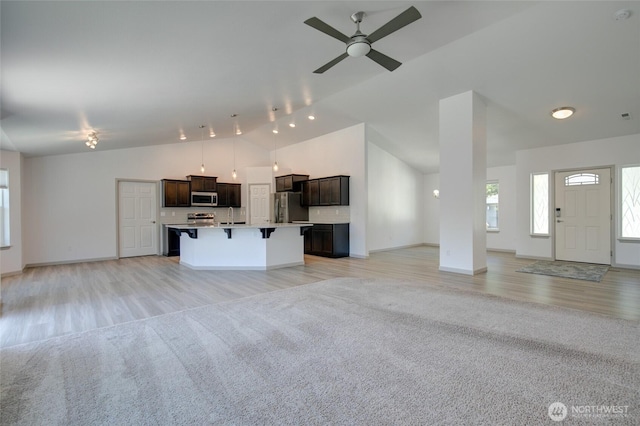 232 Jett Ct, Montesano, WA 98563 - unfurnished living room with high vaulted ceiling, light colored carpet, a ceiling fan, and light wood finished floors