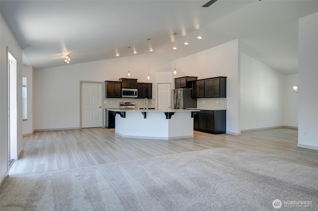 232 Jett Ct, Montesano, WA 98563 - kitchen featuring stainless steel appliances, open floor plan, a kitchen breakfast bar, dark brown cabinetry, and high vaulted ceiling