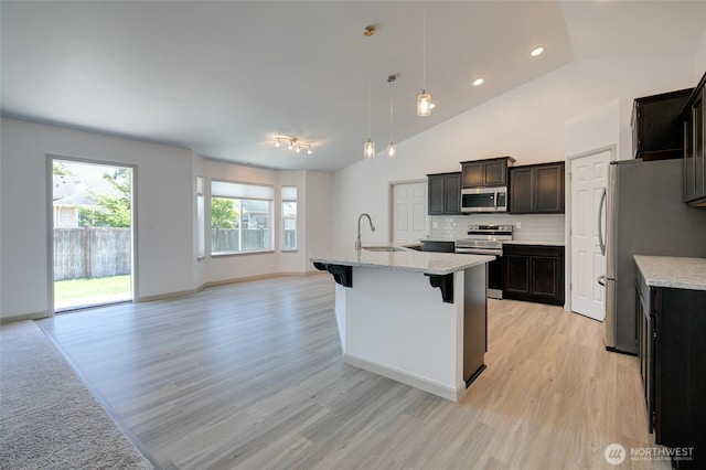 232 Jett Ct, Montesano, WA 98563 - kitchen with stainless steel appliances, light wood finished floors, open floor plan, a kitchen bar, and tasteful backsplash