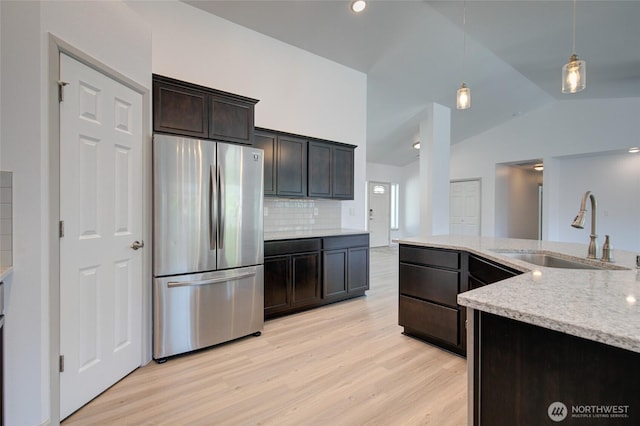 232 Jett Ct, Montesano, WA 98563 - kitchen with freestanding refrigerator, light wood-style flooring, lofted ceiling, decorative backsplash, and light stone countertops