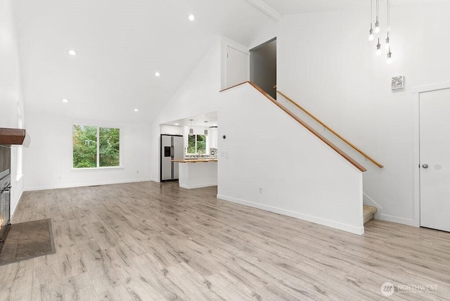 2819 SW 350th Pl, Federal Way, WA 98023 - unfurnished living room with stairs, light wood finished floors, a fireplace, high vaulted ceiling, and recessed lighting