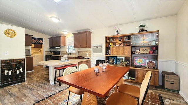 869 Mahogany Ln NW, Silverdale, WA 98383 - dining space with washer and dryer, light wood finished floors, vaulted ceiling, a wall unit AC, and a wainscoted wall