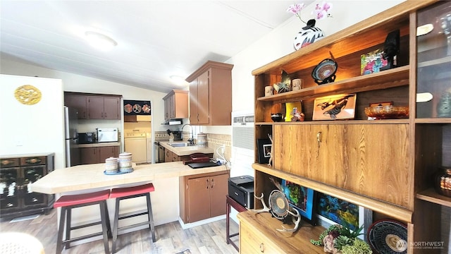 869 Mahogany Ln NW, Silverdale, WA 98383 - kitchen featuring washer and clothes dryer, lofted ceiling, open shelves, light wood-style floors, and freestanding refrigerator