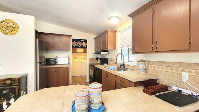 869 Mahogany Ln NW, Silverdale, WA 98383 - kitchen with separate washer and dryer, black appliances, exhaust hood, vaulted ceiling, and tile countertops