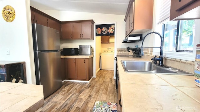 869 Mahogany Ln NW, Silverdale, WA 98383 - kitchen with freestanding refrigerator, washer / clothes dryer, vaulted ceiling, light countertops, and light wood-style floors