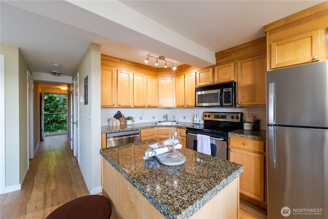 1525 Taylor Ave N Unit 505, Seattle, WA 98109 - kitchen featuring appliances with stainless steel finishes, decorative backsplash, light wood finished floors, and a center island