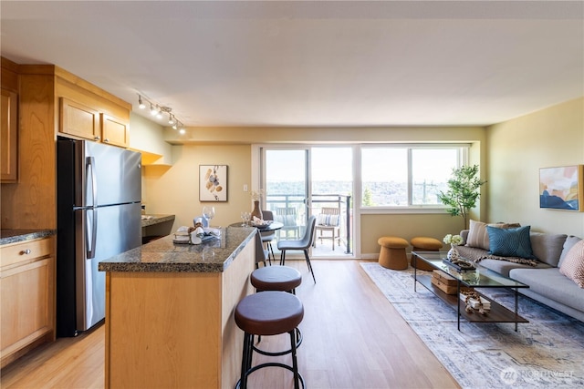 1525 Taylor Ave N Unit 505, Seattle, WA 98109 - kitchen featuring freestanding refrigerator, light wood-style flooring, a kitchen island, a kitchen breakfast bar, and open floor plan