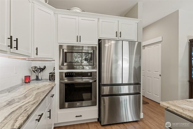 2219 Treat St SE, East Wenatchee, WA 98802 - kitchen featuring appliances with stainless steel finishes, decorative backsplash, white cabinets, light stone countertops, and light wood-type flooring