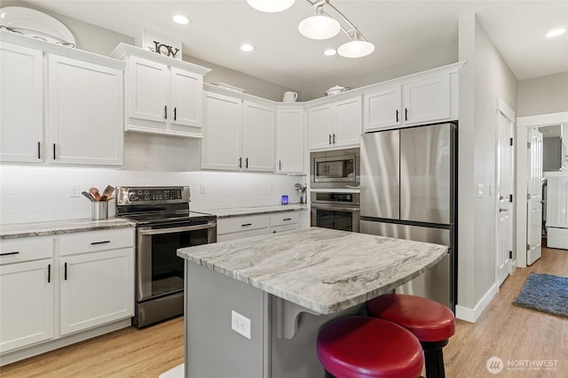 2219 Treat St SE, East Wenatchee, WA 98802 - kitchen with stainless steel appliances, light wood finished floors, white cabinetry, tasteful backsplash, and a center island