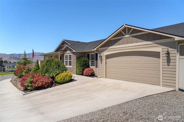 2219 Treat St SE, East Wenatchee, WA 98802 - view of front of house featuring concrete driveway, a garage, a shingled roof, a mountain view, and board and batten siding