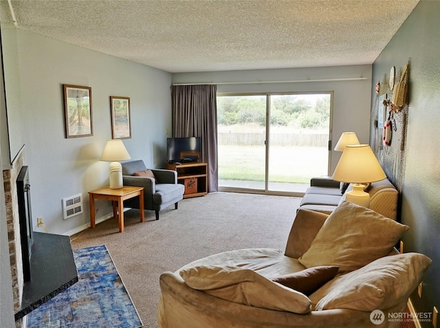615 Ocean Shores Blvd NW Unit 115, Ocean Shores, WA 98569 - living room with carpet floors, a textured ceiling, a fireplace with raised hearth, and heating unit