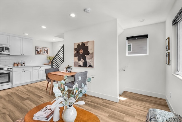 5945 41st Ave SW Unit A, Seattle, WA 98136 - kitchen with appliances with stainless steel finishes, light countertops, white cabinetry, light wood finished floors, and decorative backsplash