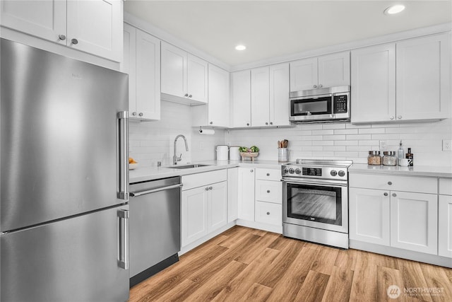 5945 41st Ave SW Unit A, Seattle, WA 98136 - kitchen featuring stainless steel appliances, light countertops, white cabinets, light wood-style floors, and tasteful backsplash