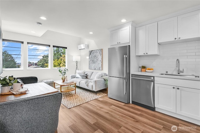 5945 41st Ave SW Unit A, Seattle, WA 98136 - kitchen with appliances with stainless steel finishes, open floor plan, a wall unit AC, backsplash, and white cabinetry