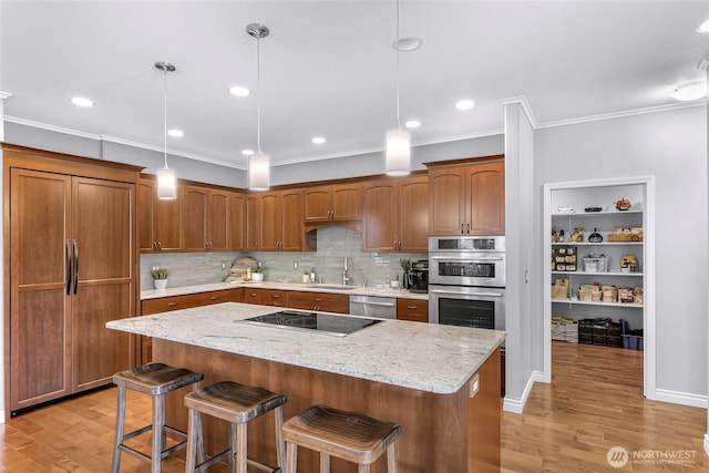 2620 Birch St, Bellingham, WA 98226 - kitchen featuring appliances with stainless steel finishes, ornamental molding, a breakfast bar, light wood-style flooring, and a center island