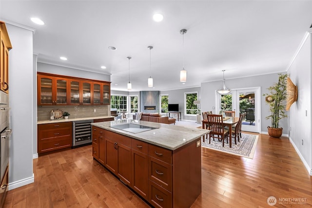 2620 Birch St, Bellingham, WA 98226 - kitchen featuring wine cooler, hardwood / wood-style floors, a kitchen island with sink, ornamental molding, and glass insert cabinets