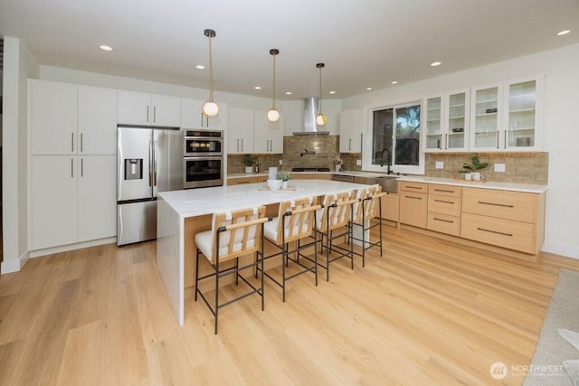 14737 56th Ave S, Tukwila, WA 98168 - kitchen with appliances with stainless steel finishes, wall chimney exhaust hood, light wood-style flooring, a breakfast bar, and backsplash