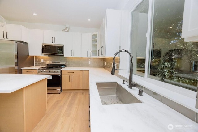 14737 56th Ave S, Tukwila, WA 98168 - kitchen with appliances with stainless steel finishes, light wood-style flooring, backsplash, light countertops, and glass insert cabinets