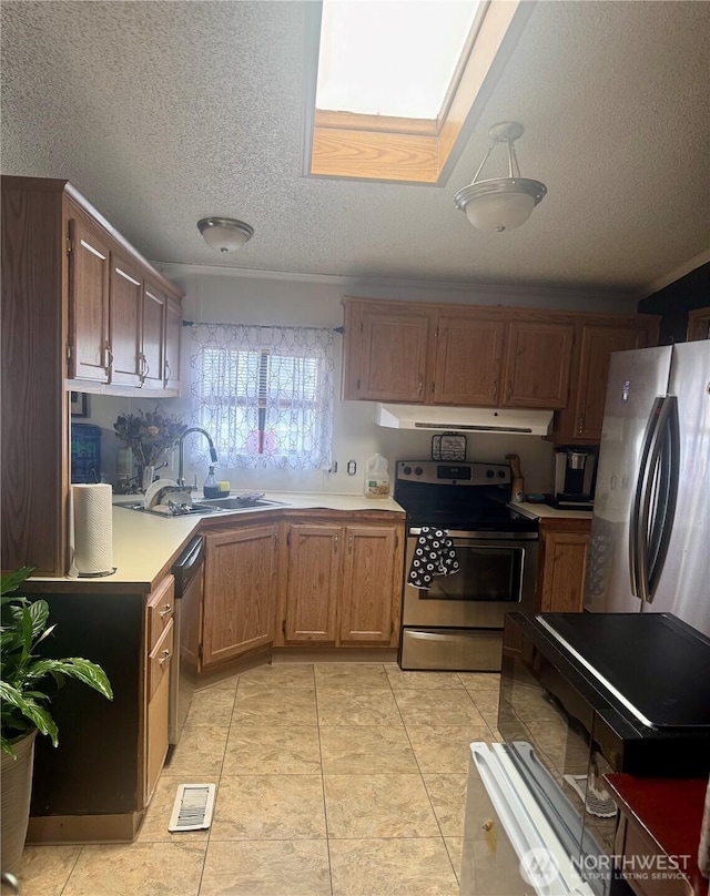 7619 156th Street Ct E Unit 9, Puyallup, WA 98375 - kitchen featuring appliances with stainless steel finishes, under cabinet range hood, a textured ceiling, light countertops, and light tile patterned floors