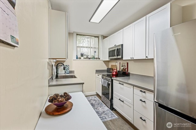 7 Harrison St Unit 5, Seattle, WA 98109 - kitchen with appliances with stainless steel finishes, dark wood-style flooring, and white cabinets