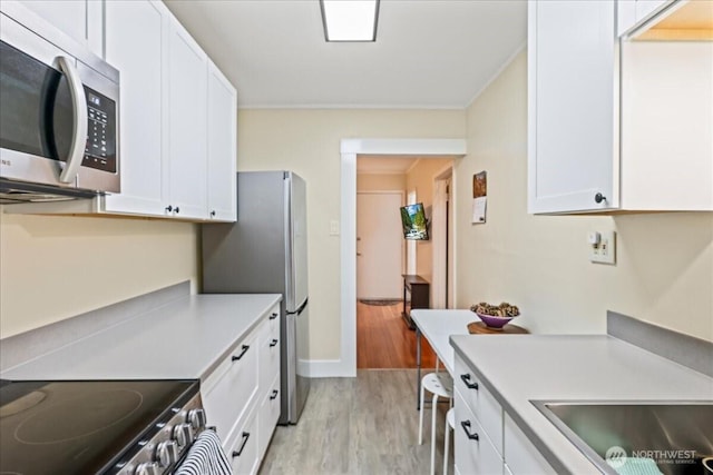7 Harrison St Unit 5, Seattle, WA 98109 - kitchen featuring appliances with stainless steel finishes, light wood-style flooring, white cabinetry, light countertops, and ornamental molding