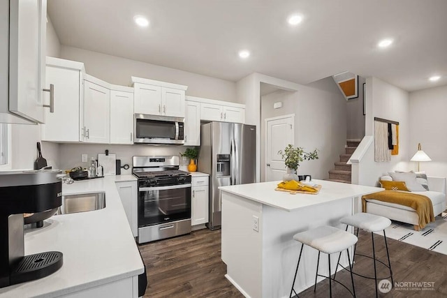 224 18th Dr Unit 96, Snohomish, WA 98290 - kitchen with stainless steel appliances, a breakfast bar area, dark wood finished floors, light countertops, and white cabinets