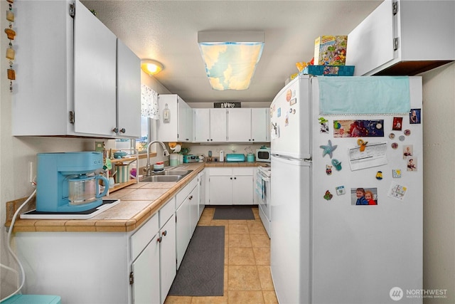 11613 63rd Street Ct E, Puyallup, WA 98372 - kitchen with white appliances, white cabinetry, light tile patterned floors, and tile counters