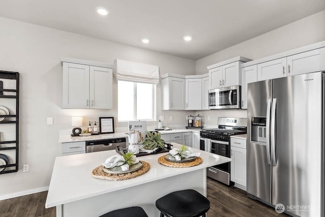 214 18th Dr Unit 100, Snohomish, WA 98290 - kitchen featuring appliances with stainless steel finishes, light countertops, dark wood-style floors, a kitchen breakfast bar, and a kitchen island