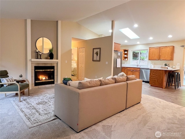104 Puget Loop, Port Ludlow, WA 98365 - living area with a skylight, a tiled fireplace, vaulted ceiling, recessed lighting, and light wood-type flooring