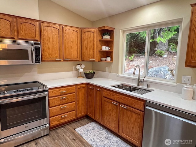 104 Puget Loop, Port Ludlow, WA 98365 - kitchen featuring appliances with stainless steel finishes, light countertops, wood finished floors, brown cabinetry, and vaulted ceiling