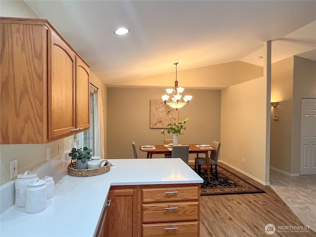 104 Puget Loop, Port Ludlow, WA 98365 - kitchen with a peninsula, lofted ceiling, a chandelier, light countertops, and hanging light fixtures
