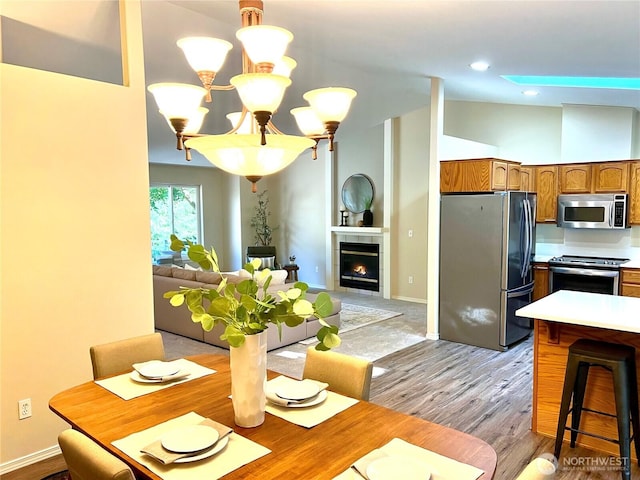 104 Puget Loop, Port Ludlow, WA 98365 - dining room featuring a chandelier, lofted ceiling, light wood-style flooring, and a fireplace