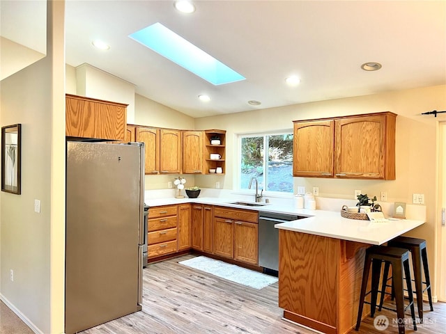 104 Puget Loop, Port Ludlow, WA 98365 - kitchen featuring stainless steel appliances, a peninsula, brown cabinets, lofted ceiling, and light wood-style floors