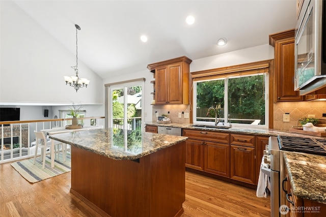 28314 180th Ave SE, Covington, WA 98042 - kitchen featuring appliances with stainless steel finishes, light wood-style flooring, dark stone countertops, a kitchen island, and vaulted ceiling