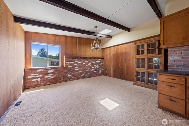 714 Canterbury Rd NW, Soap Lake, WA 98851 - unfurnished living room with a chandelier, beam ceiling, wooden walls, brick wall, and carpet floors