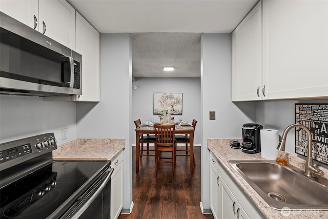 6105 N 16th St Unit N203, Tacoma, WA 98406 - kitchen featuring range with electric stovetop, stainless steel microwave, dark wood-type flooring, white cabinets, and a textured ceiling