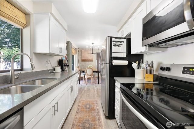 145 7th St, Gold Bar, WA 98251 - kitchen featuring appliances with stainless steel finishes, white cabinetry, light wood-type flooring, a chandelier, and dark stone counters