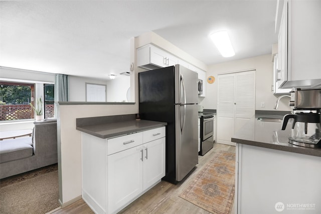 145 7th St, Gold Bar, WA 98251 - kitchen with stainless steel appliances, dark countertops, white cabinets, and light wood-style floors